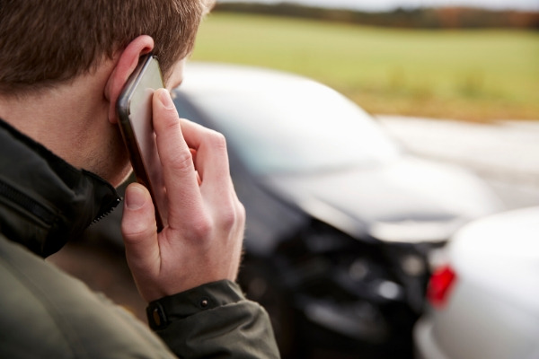 Young male motorist involved in car accident calling insurance company or recovery service