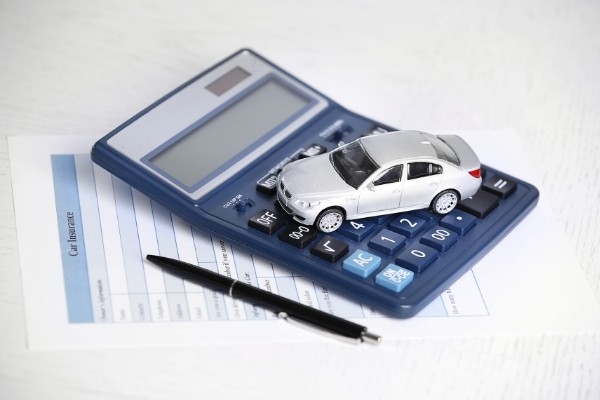 Toy car, car insurance documents and calculator on table