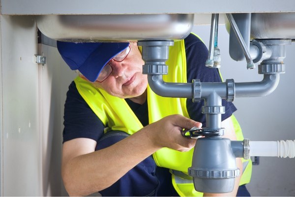 Plumber repairing sink with adjustable wrench